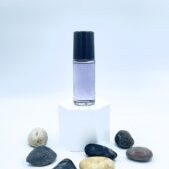 Purple roller bottle on white pedestal with stones