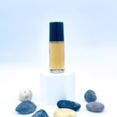 Amber perfume bottle on white pedestal with stones