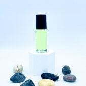 Green essential oil bottle on pedestal with stones